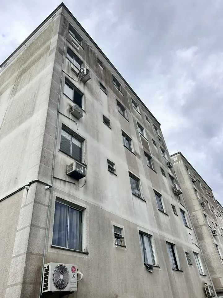 Prédio residencial de cinco andares com a fachada encardida e manchada de sujeira