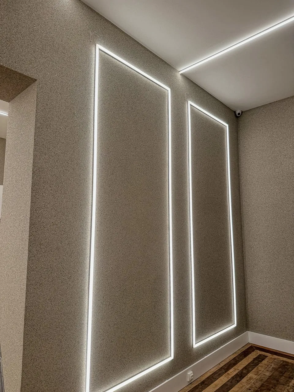 Parede interna revestida com pedras naturais em tom areia, com fita de LED embutida